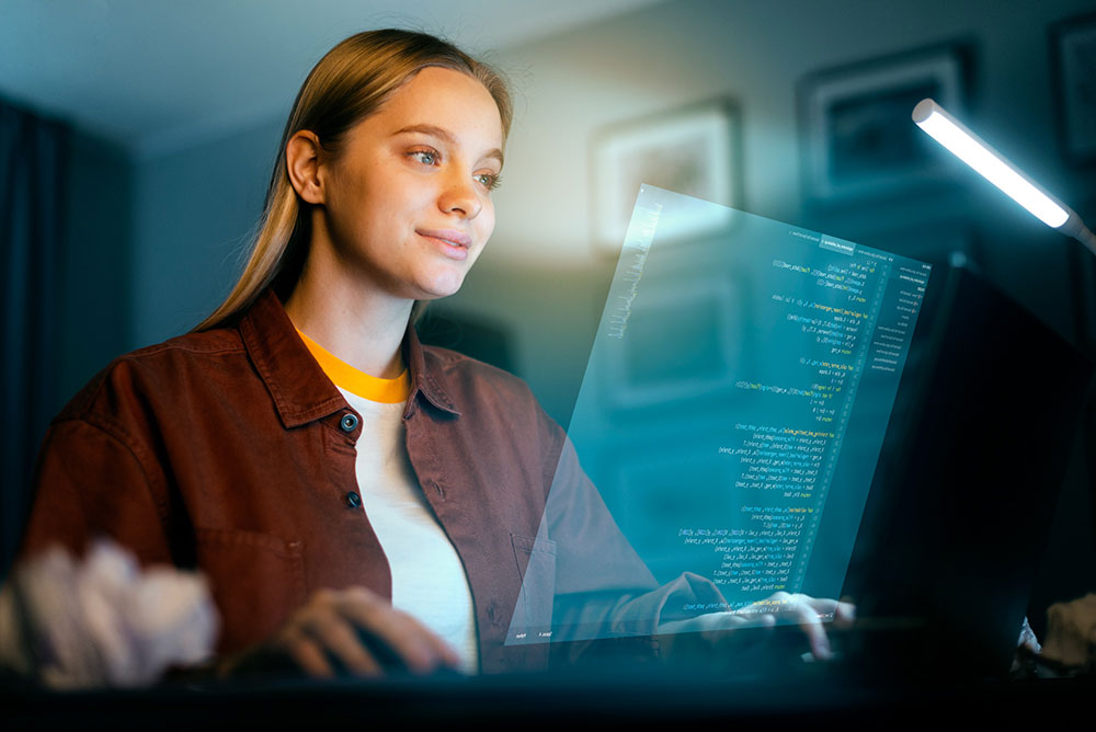 Woman coding at desktop computer with dim light
