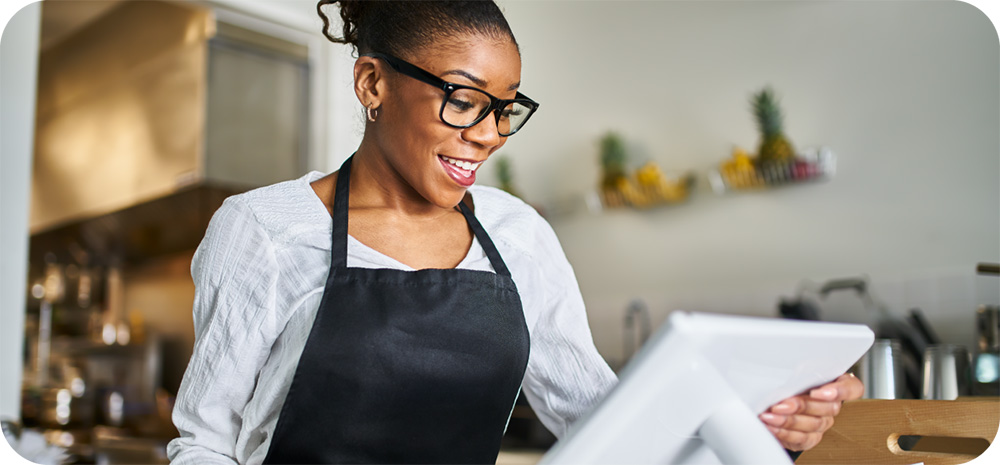 Woman with glasses smiling while working on a computer